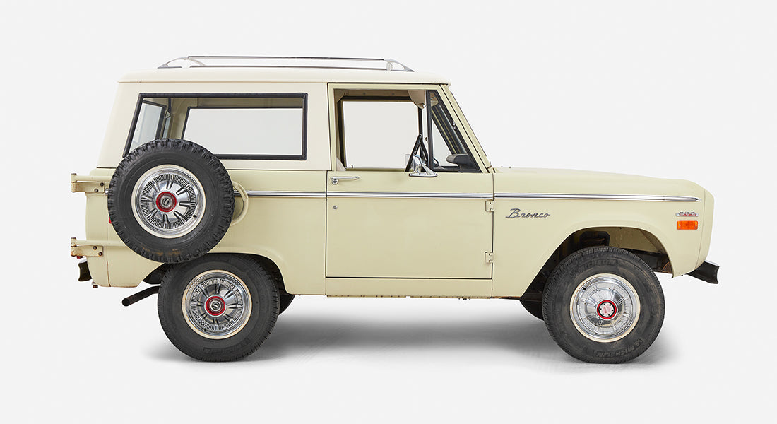 Side view of Classic Ford Bronco showing two doors, spare tire mounted on back, and mid-size SUV profile