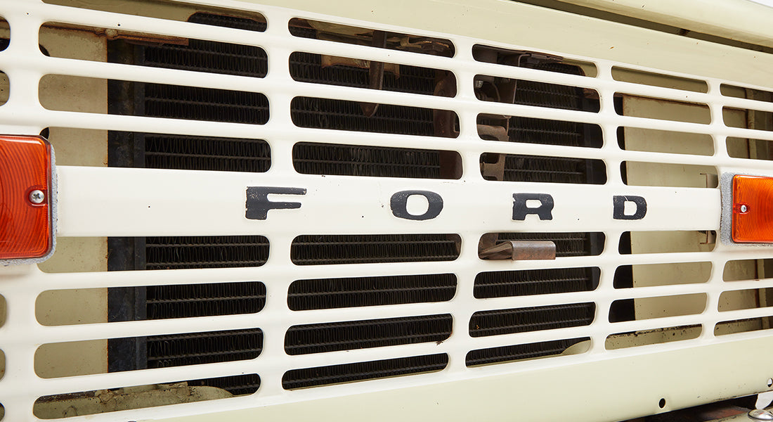 Close-up of white front grille with black Ford letters and amber side marker light on Classic Ford Bronco