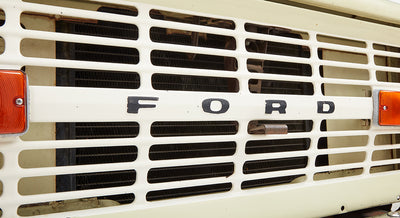Close-up of white front grille with black Ford letters and amber side marker light on Classic Ford Bronco