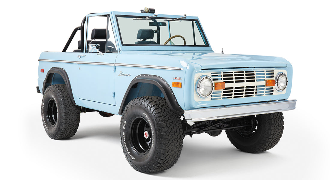 Classic Ford Bronco baby blue front three-quarter view featuring round headlights and lifted suspension.