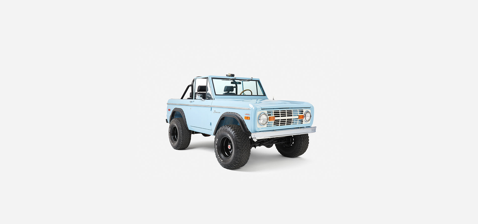 Front three-quarter view of a baby blue Classic Ford Bronco with black fender flares and large tires