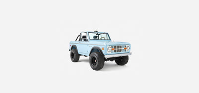 Front three-quarter view of a baby blue Classic Ford Bronco with black fender flares and large tires