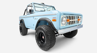 Front view close-up of a baby blue Classic Ford Bronco highlighting headlights and grille