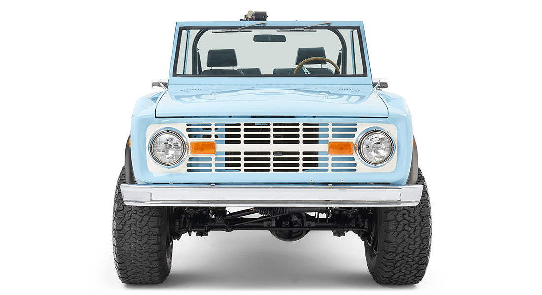 Classic Ford Bronco baby blue front view showing the grille, headlights, and bumper.