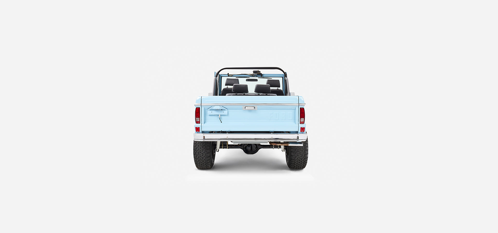 Rear view of baby blue Classic Ford Bronco with white bumper and black wheels