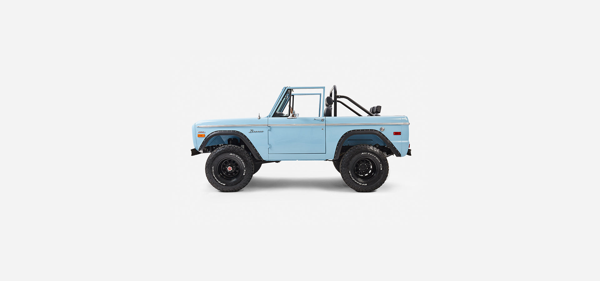 Side shot of baby blue Classic Ford Bronco convertible with doors and roll cage