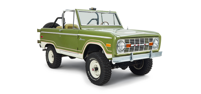 Three-quarter front view of a green and white Classic Ford Bronco with no roof and off-road tires.