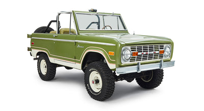 Classic Ford Bronco in green with white roof removed, white wheels, and off-road tires at angled front view
