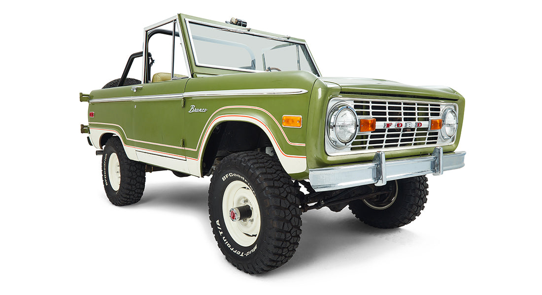 Three-quarter front view of a green and white Classic Ford Bronco with off-road tires.