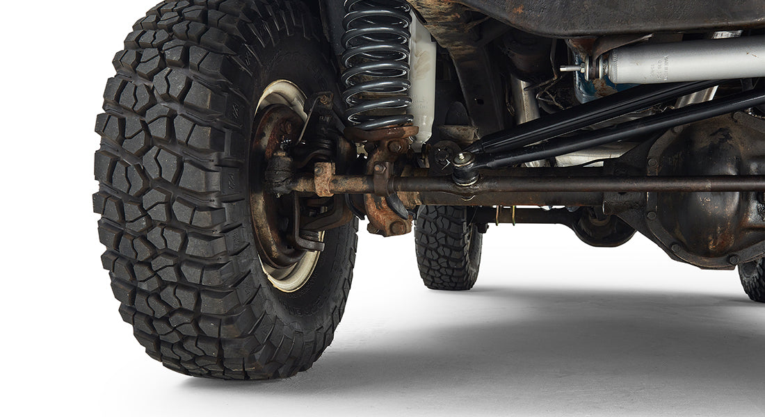 Close-up of the rear axle, coil spring suspension, and off-road tire of a Classic Ford Bronco
