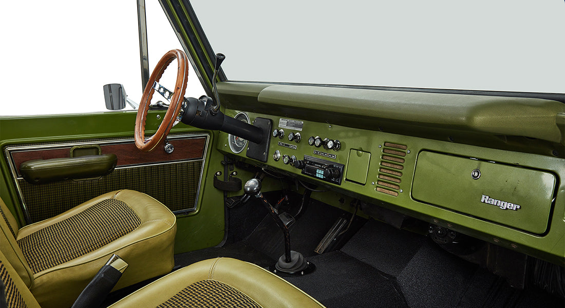 Interior view of a Classic Ford Bronco's front seats, steering wheel, and dashboard