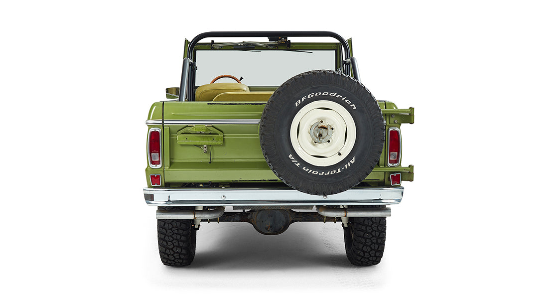 Rear view of a green Classic Ford Bronco with a spare tire mounted on the back