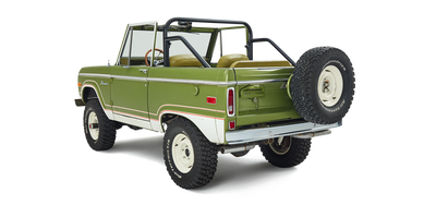 Three-quarter rear view of a green and white Classic Ford Bronco angled to the right with off-road tires.