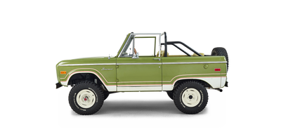 Side profile of a green and white Classic Ford Bronco with no roof and off-road tires.