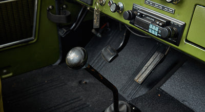 Close-up of the interior of green Classic Ford Bronco focusing on gear shift and pedals.