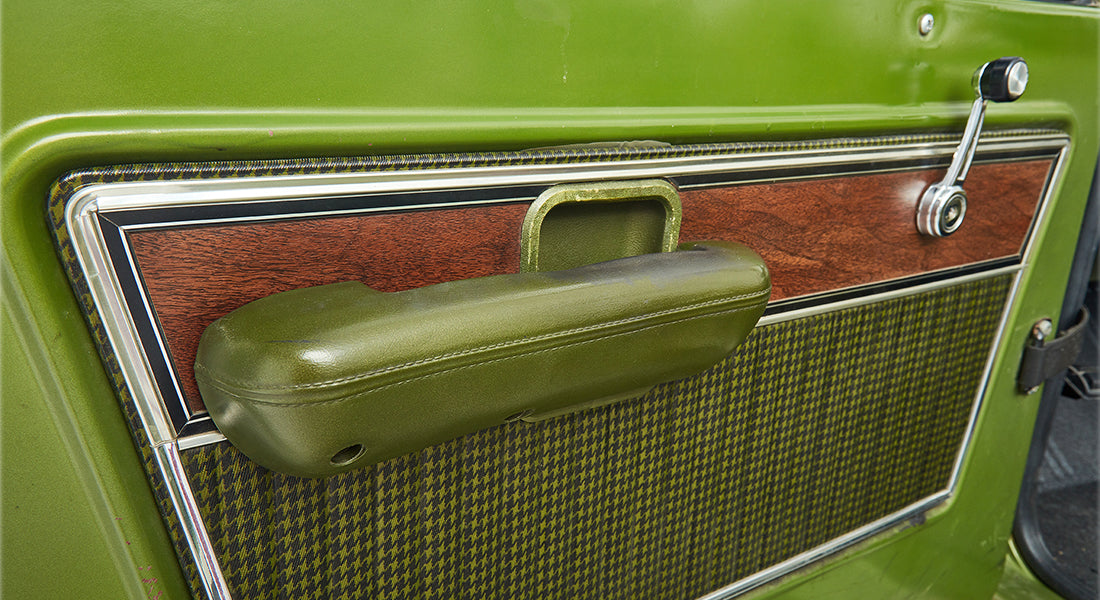 Detailed view of the passenger side door panel and armrest in a green Classic Ford Bronco