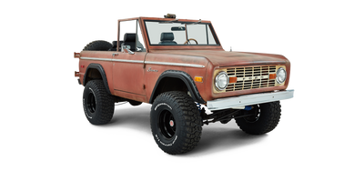 Front driver angle view of a red Classic Ford Bronco with patina finish and lifted suspension