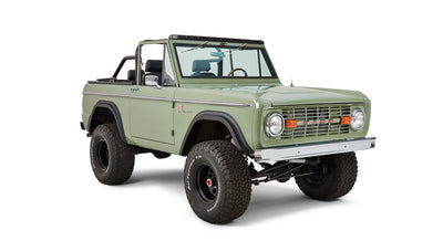 Three-quarter front view of Classic Ford Bronco showing green body, black wheels, and off-road tires