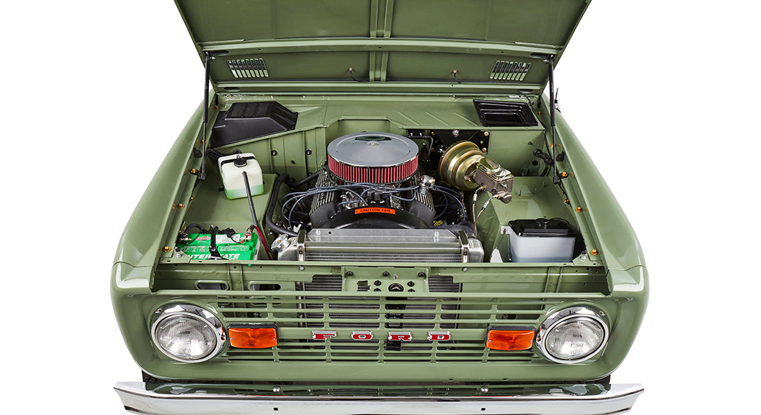 Front view of green Classic Ford Bronco with hood open exposing engine and radiator details.