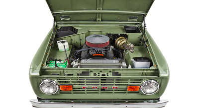 Front view of green Classic Ford Bronco with hood open exposing engine and radiator details.