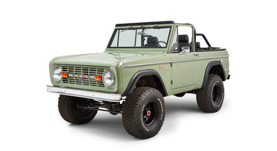 Three-quarter front view of green Classic Ford Bronco showing tires, headlights, and grille lettering.
