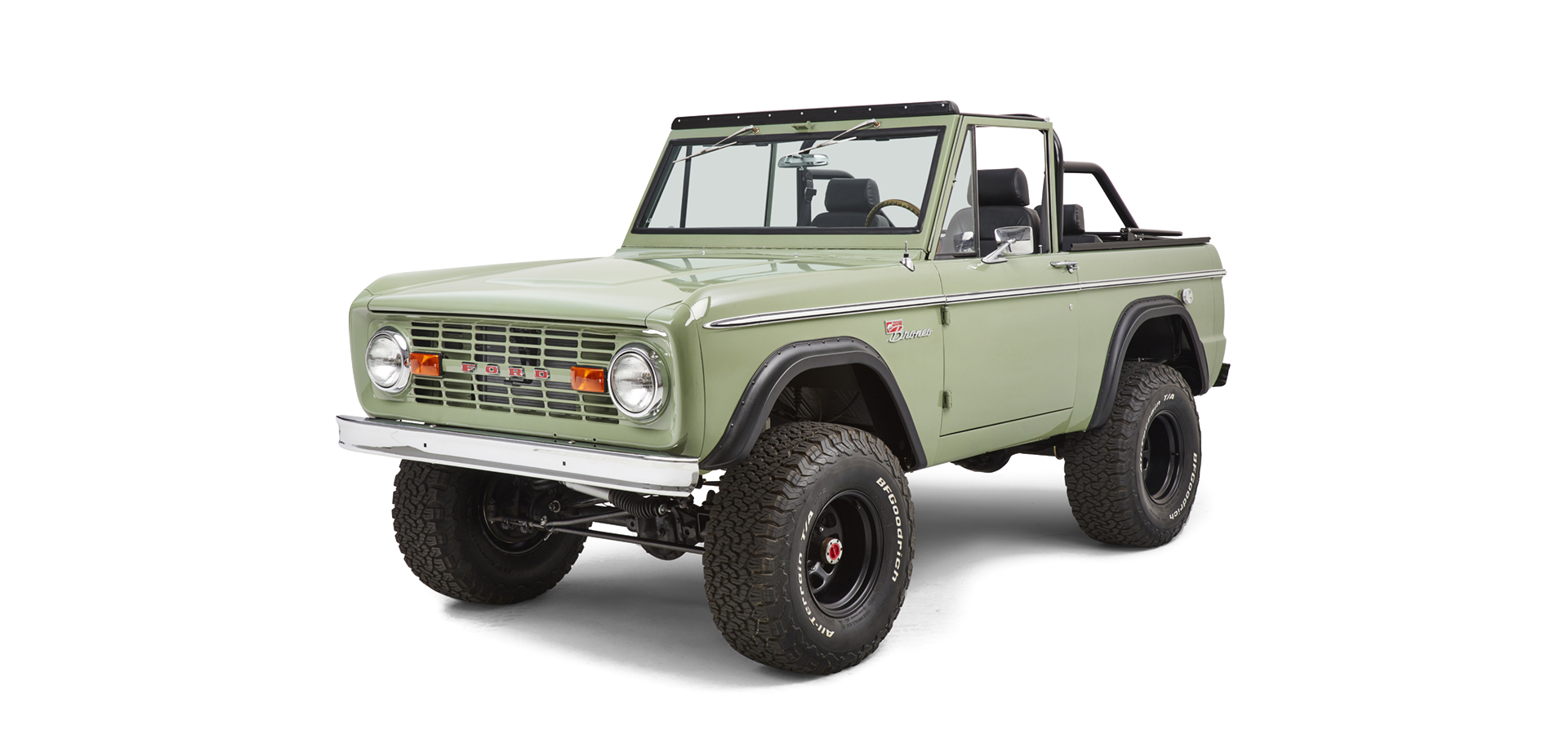 Classic Ford Bronco in green with black seats, black steel wheels, and large off-road tires