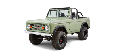 Classic Ford Bronco in green with black seats, black steel wheels, and large off-road tires