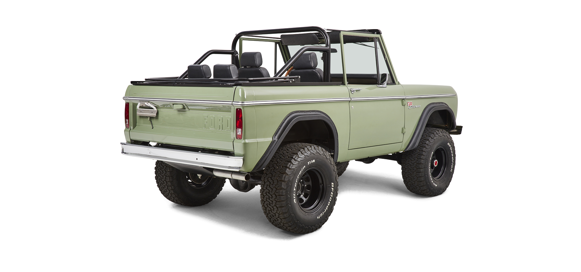 Rear-side view of a green Classic Ford Bronco with black roll cage and off-road tires