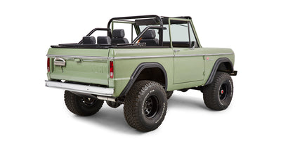 Side rear quarter view of green Classic Ford Bronco with open top and large off-road tires.