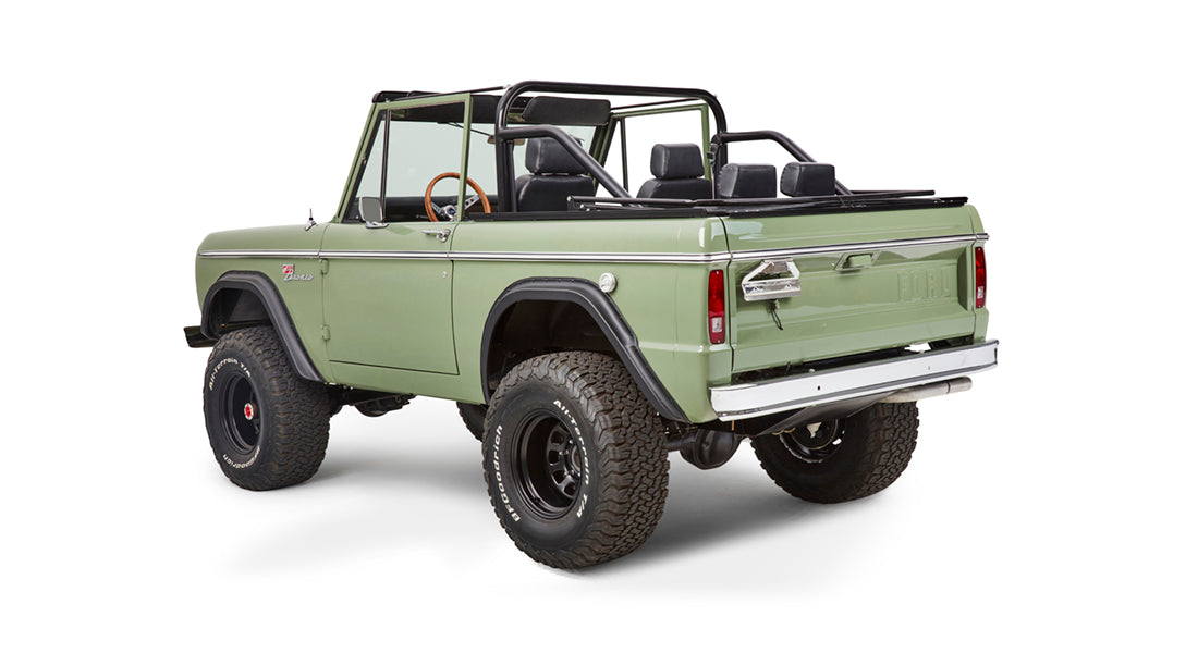 Rear three-quarter view of green Classic Ford Bronco with roll cage and off-road tires