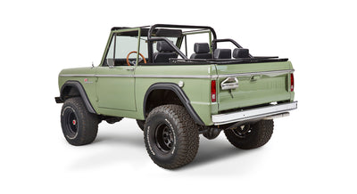 Rear three-quarter view of green Classic Ford Bronco with roll cage and off-road tires