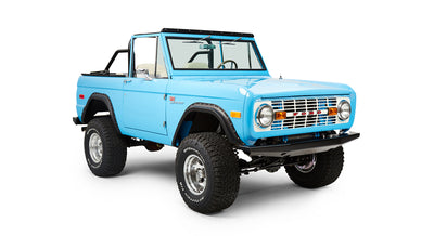 Classic Ford Bronco in light blue shown angled front passenger side with off-road tires and open top