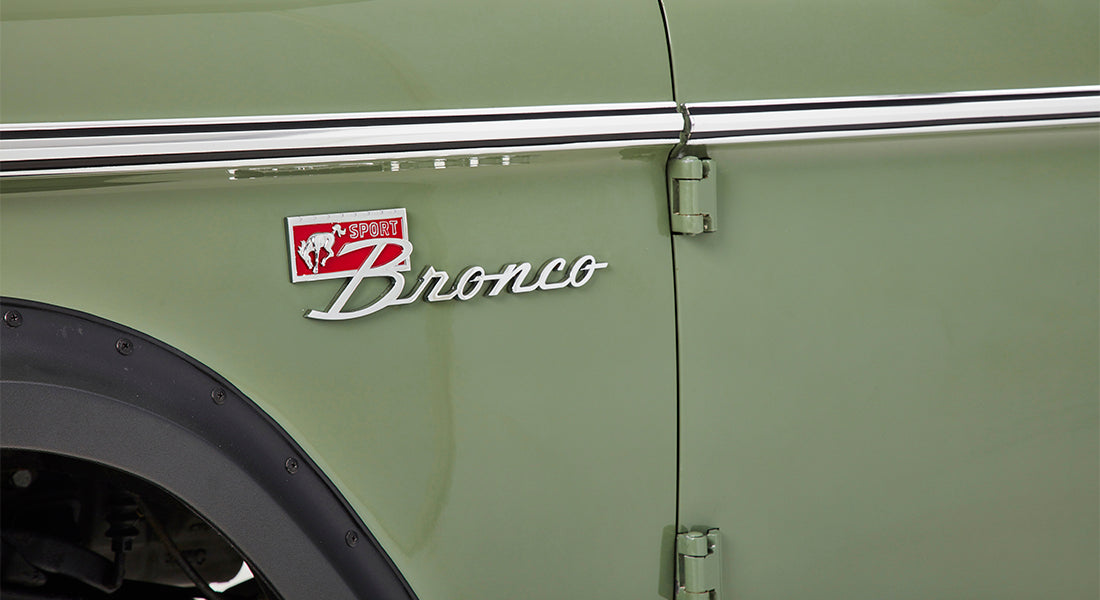 Dashboard inside Classic Ford Bronco showing speedometer, steering column, and wood steering wheel