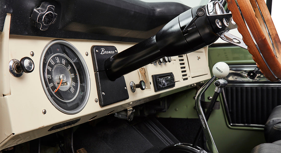 Black speaker and seatbelt on black interior panel behind seat inside Classic Ford Bronco