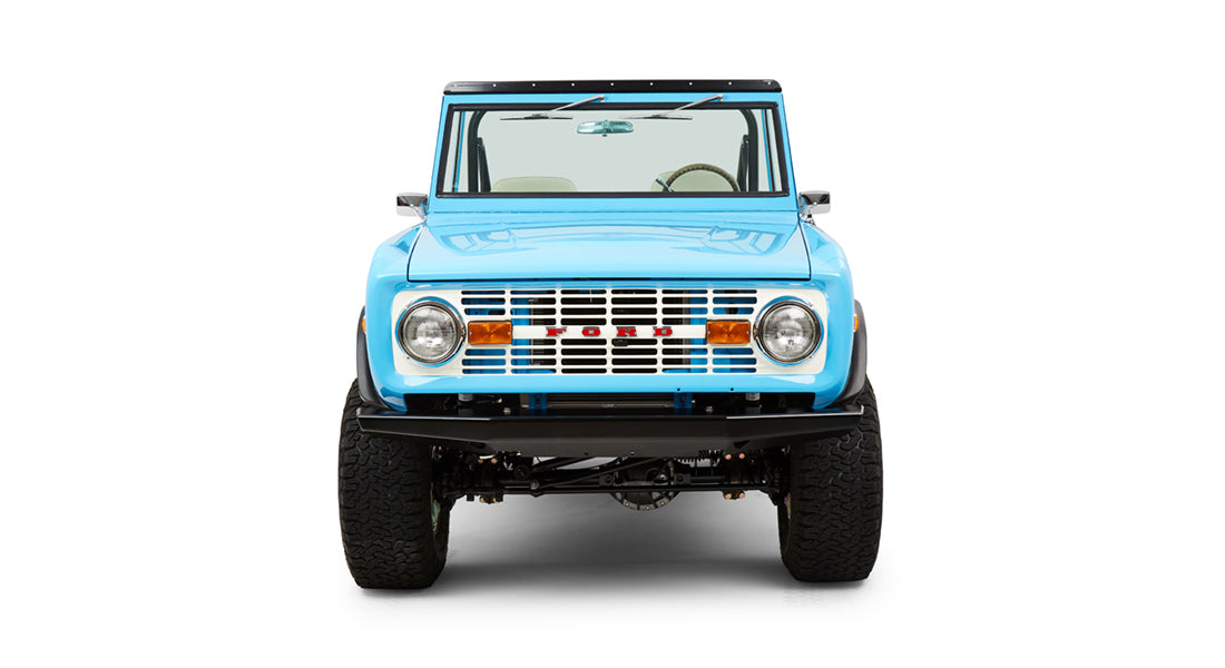 Front view of Classic Ford Bronco in blue with round headlights and white grille showing red FORD letters