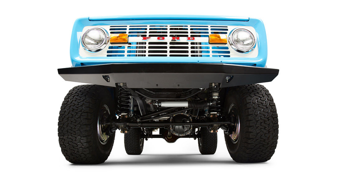 Undercarriage front view showing suspension and tires of a classic Ford Bronco with black bumper