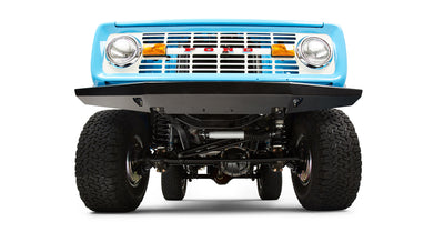 Undercarriage front view showing suspension and tires of a classic Ford Bronco with black bumper