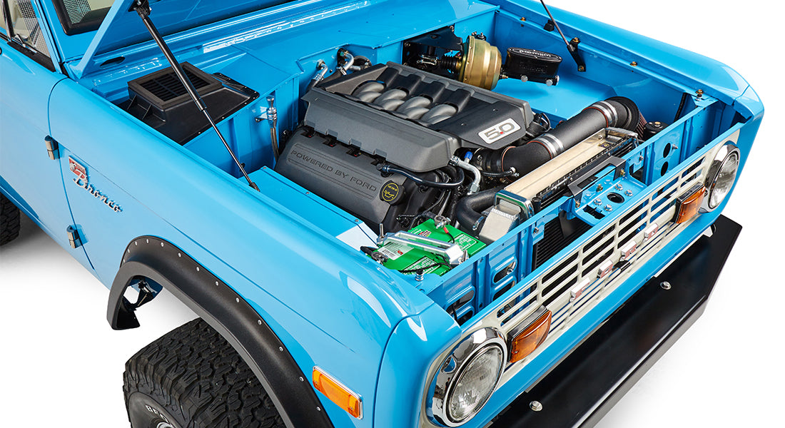 Blue Classic Ford Bronco engine bay with 5.0 liter V8 engine and black air intake tube