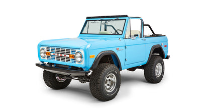 Three-quarter front view of blue Classic Ford Bronco with chrome wheels and off-road tires