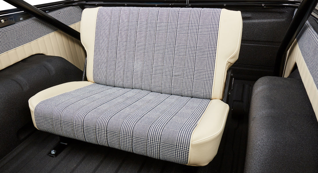 Rear bench seat inside Classic Ford Bronco with cream and checked fabric upholstery