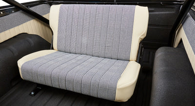Rear bench seat inside Classic Ford Bronco with cream and checked fabric upholstery