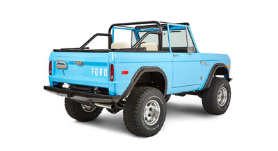Three-quarter rear view of blue Classic Ford Bronco showing open top, rear gate, and off-road tires