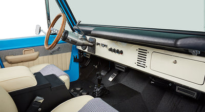 Dashboard and steering wheel inside Classic Ford Bronco with black and cream interior accents