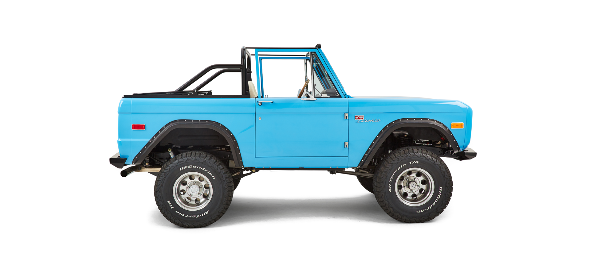 Side view of a bright blue Classic Ford Bronco with off-road tires and no roof.