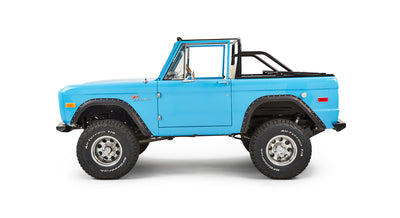 Classic Ford Bronco side view with driver door visible, blue body, and lifted suspension