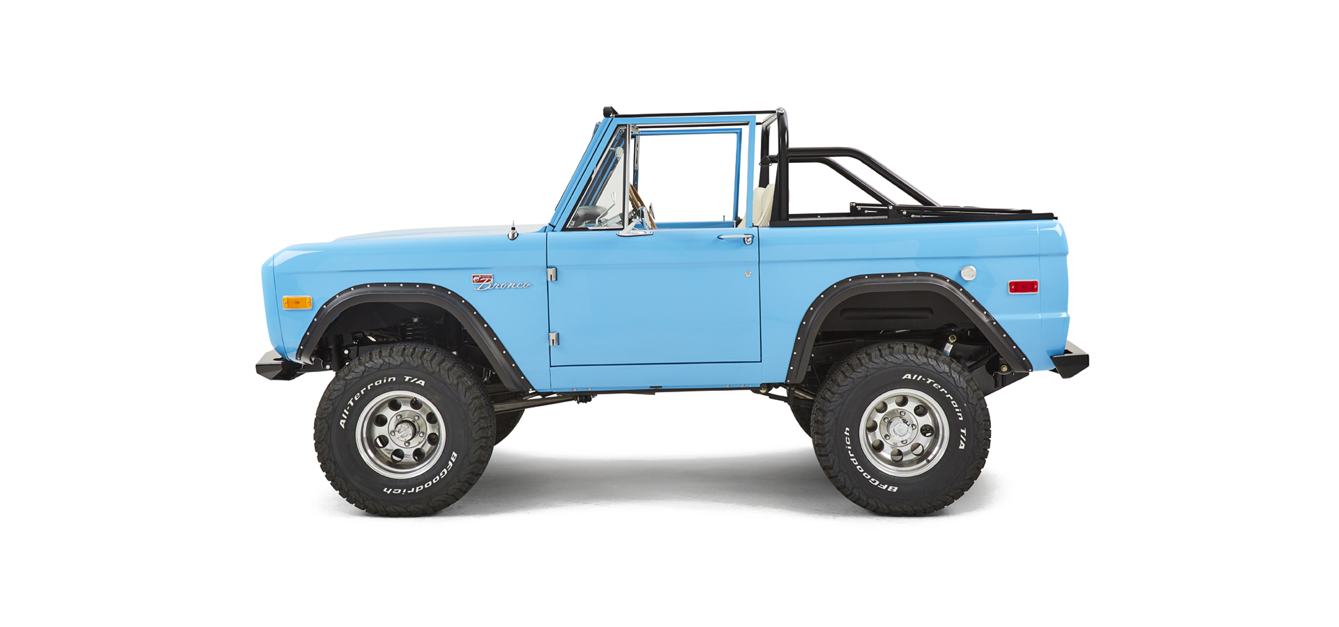 Side view of a bright blue Classic Ford Bronco with a black roll cage and no roof.