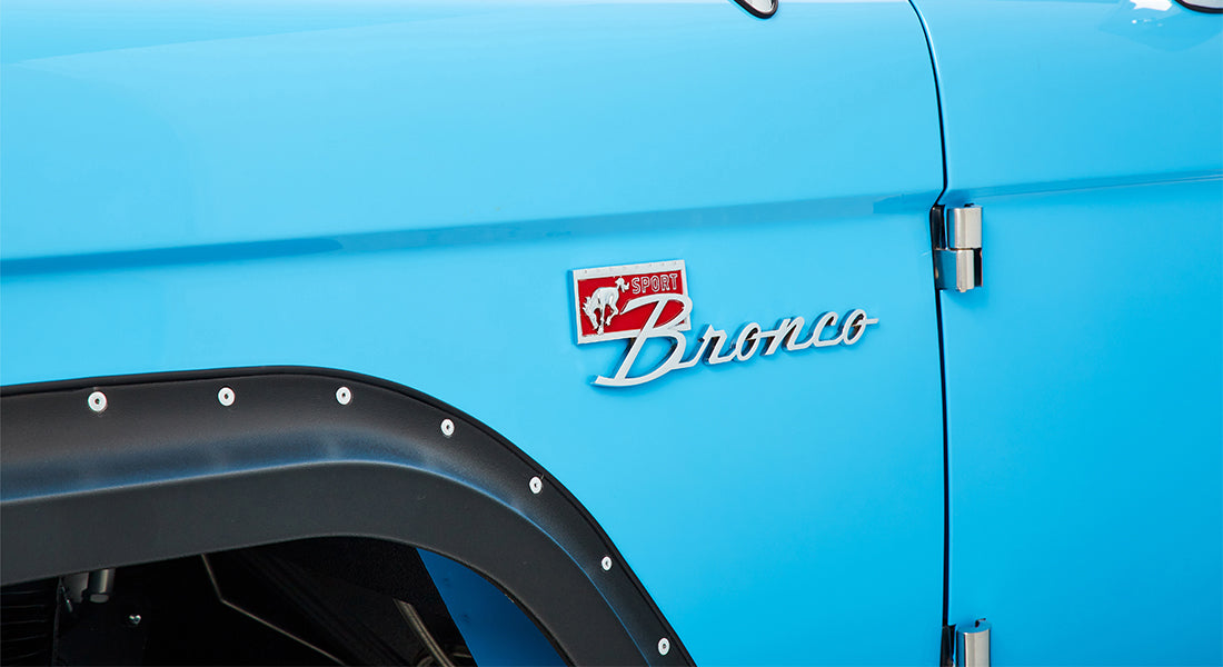 Side detail of blue Classic Ford Bronco showing sport Bronco emblem above black fender flare