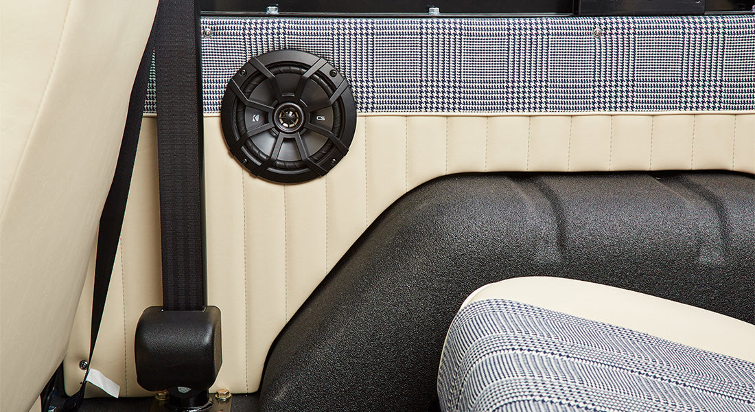 Interior section of Classic Ford Bronco showing seatbelt and black speaker mounted on beige panel
