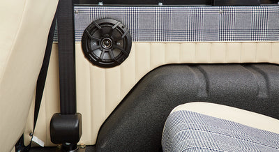 Interior section of Classic Ford Bronco showing seatbelt and black speaker mounted on beige panel