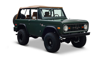 Three-quarter front view of Classic Ford Bronco in dark forest green with tan soft top against white background